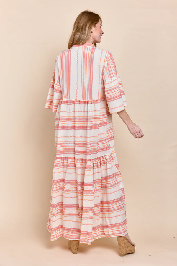 Woman wearing flowy 3/4 sleeve maxi dress with pink stripes all over