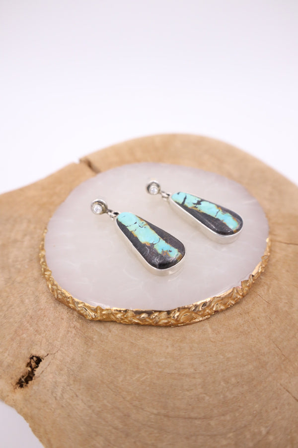 Black Jack turquoise in the shape of a teardrop in a sterling silver bezel with diamond posts