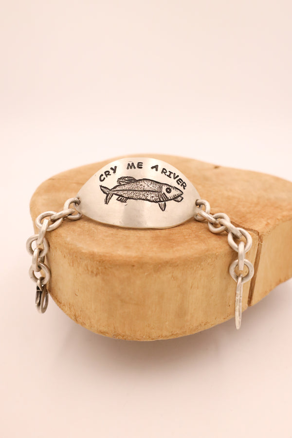 Sterling silver bracelet with center pendant that says "Cry Me A River" with chain ends 