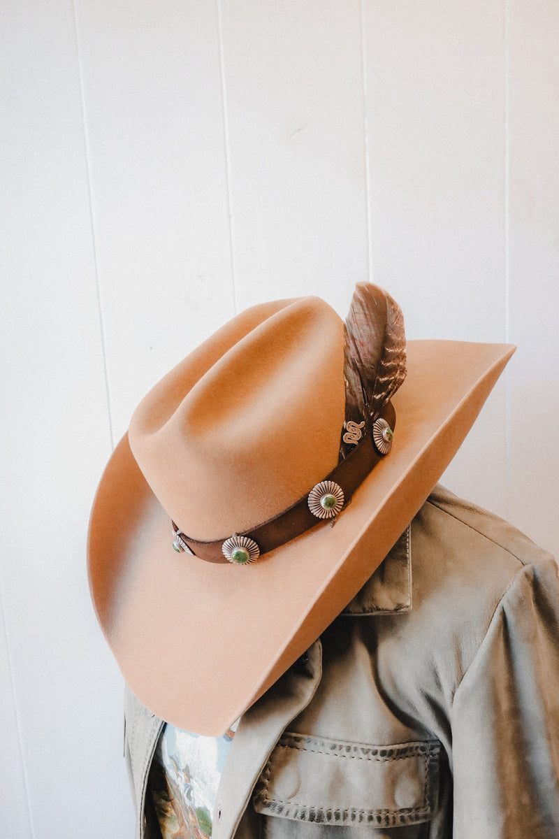 Crafted from brown leather, this hatband features 5 intricately designed pieces of turquoise surrounded by sterling silver sunbeams