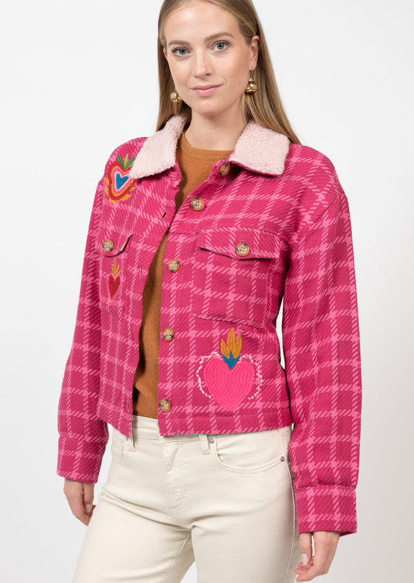 Woman wearing pink tweed jacket with embroidered heart with crowns 