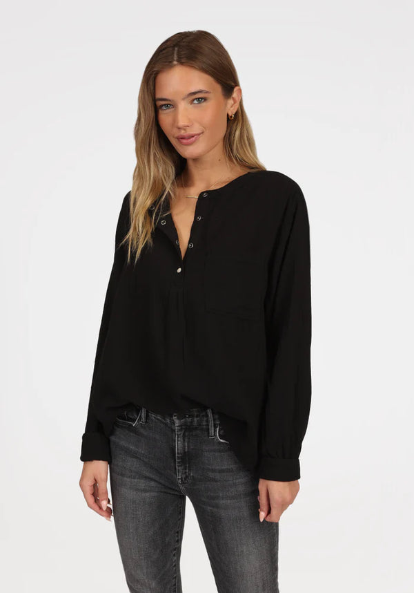 Woman wearing long sleeve black shirt with button snaps at the top 