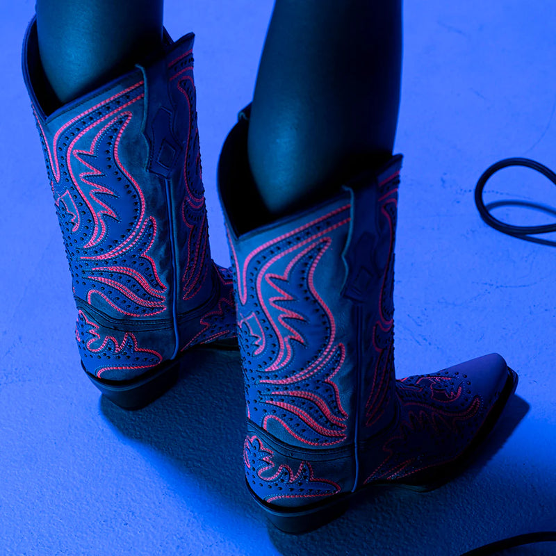 CORRAL WOMEN'S BLACKLIGHT NEON BOOTS, worn in the dark with pink outlines glowing viewed from the back