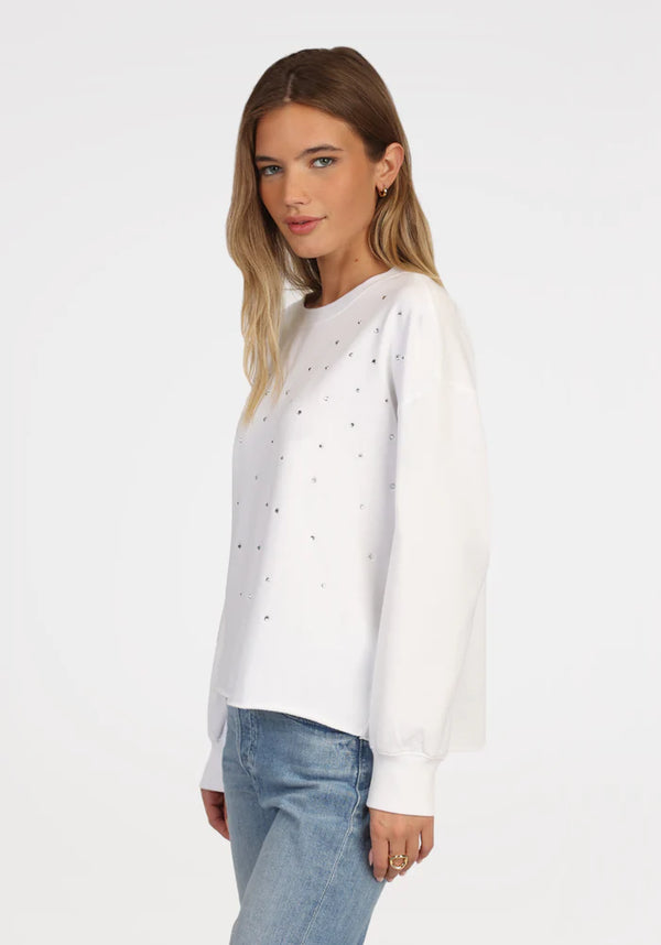 Woman wearing white sweatshirt with rhinestones all over the front