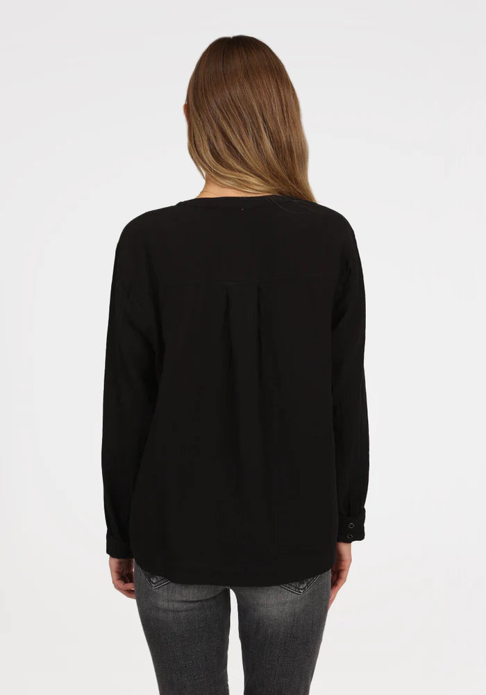 Woman wearing long sleeve black shirt with button snaps at the top