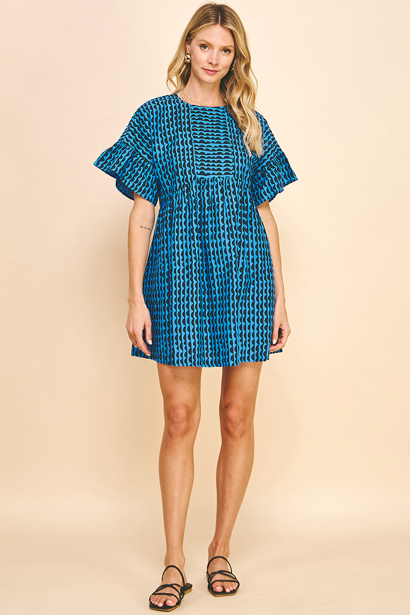 Woman wearing short puffy sleeve mini dress with navy and blue pattern