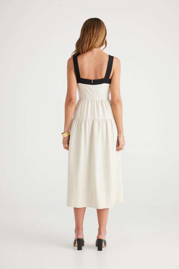 Woman wearing midi dress in cream with structured black lines contouring the upper portion of the dress