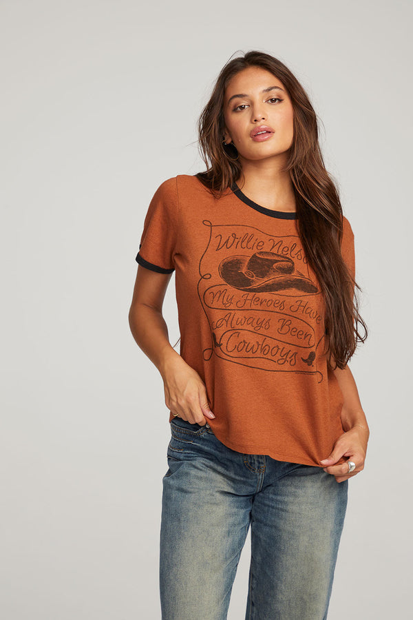 WOMAN WEARING DEEP ORANGE GRAPHIC TEE WITH WORDS "WILLIE NELSON MY HEROES HAVE ALWAYS BEEN COWBOYS"