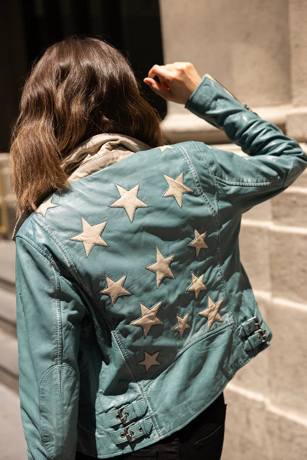 White stars on the back of a deep blue leather jacket with asymmetrical zipper on the front of the jacket  