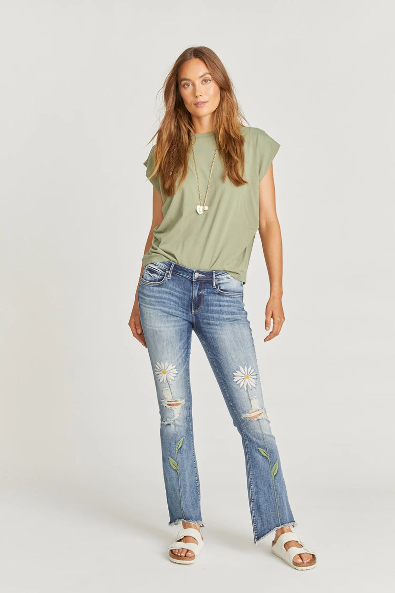 Medium wash Eva boot cut jean featuring rips on the knees, a high low frayed hem and two daisy flowers, one embroidered on each front leg.