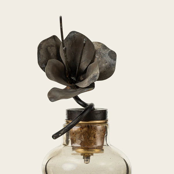 Glass vase with cast iron flower sticking out