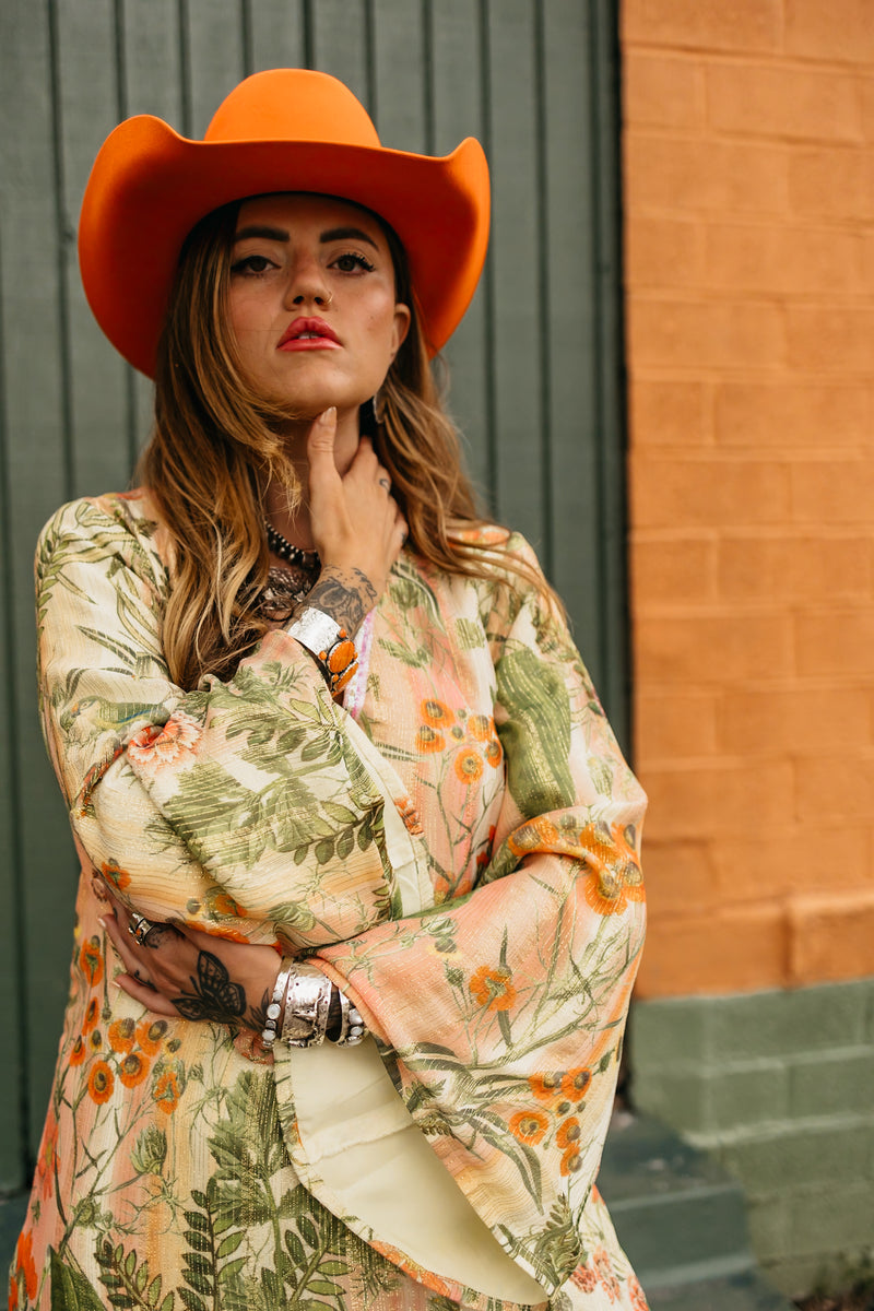 Woman wearing floral kaftan with long sleeves, double side slits and metallic gold detail