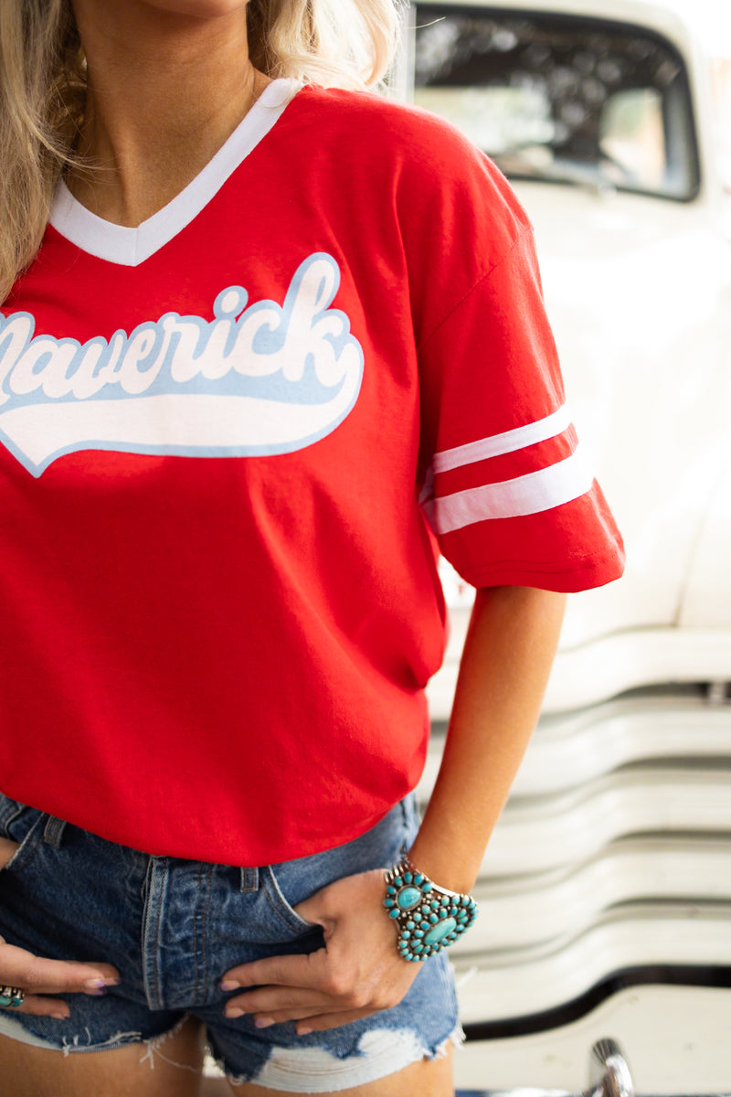 Girl wearing red vintage inspired baseball tee with white stripes on the short sleeves, vintage font spelling "Maverick" on the front and "Cowtown '87" on the back
