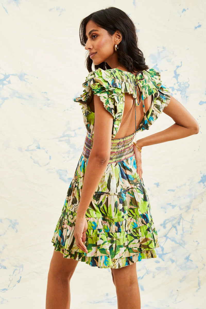 Woman wearing mini dress with ruffles on the shoulders in a leaf print