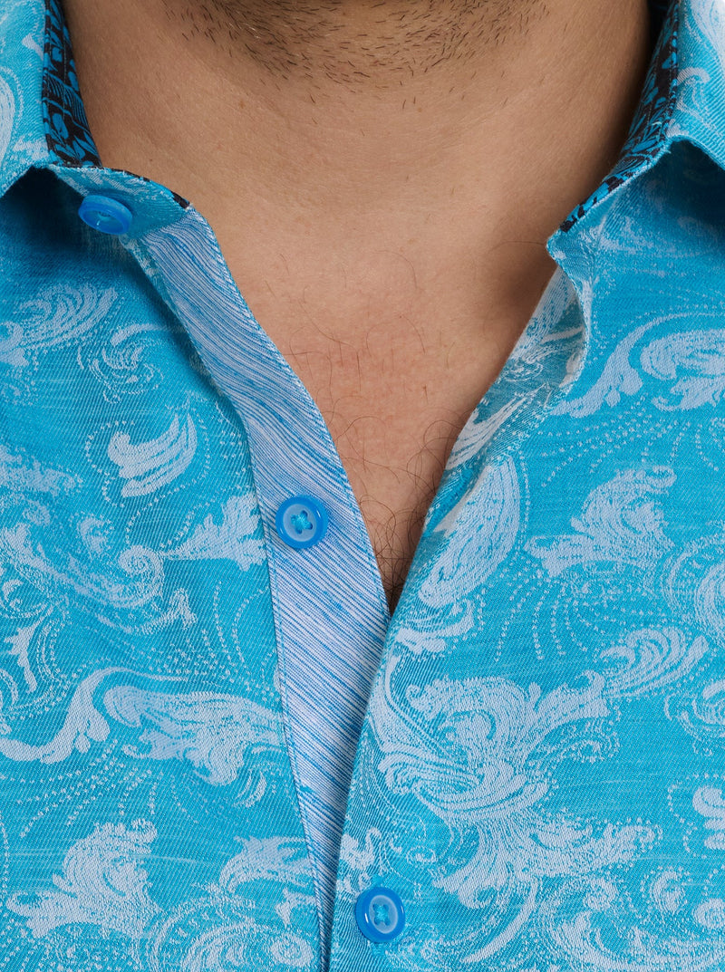 Man wearing shirt sleeve button down shirt with ornate detail in a monochromatic turquoise
