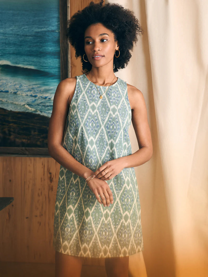 Woman wearing sleeveless dress with geometric pattern in a green and cream colorway