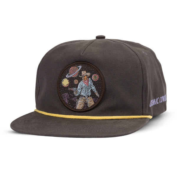 Grey snapback hat with patch of a cowboy drawing his gun with planets all around him, yellow rope detail and "cosmic cowboy" script on the side of the cap