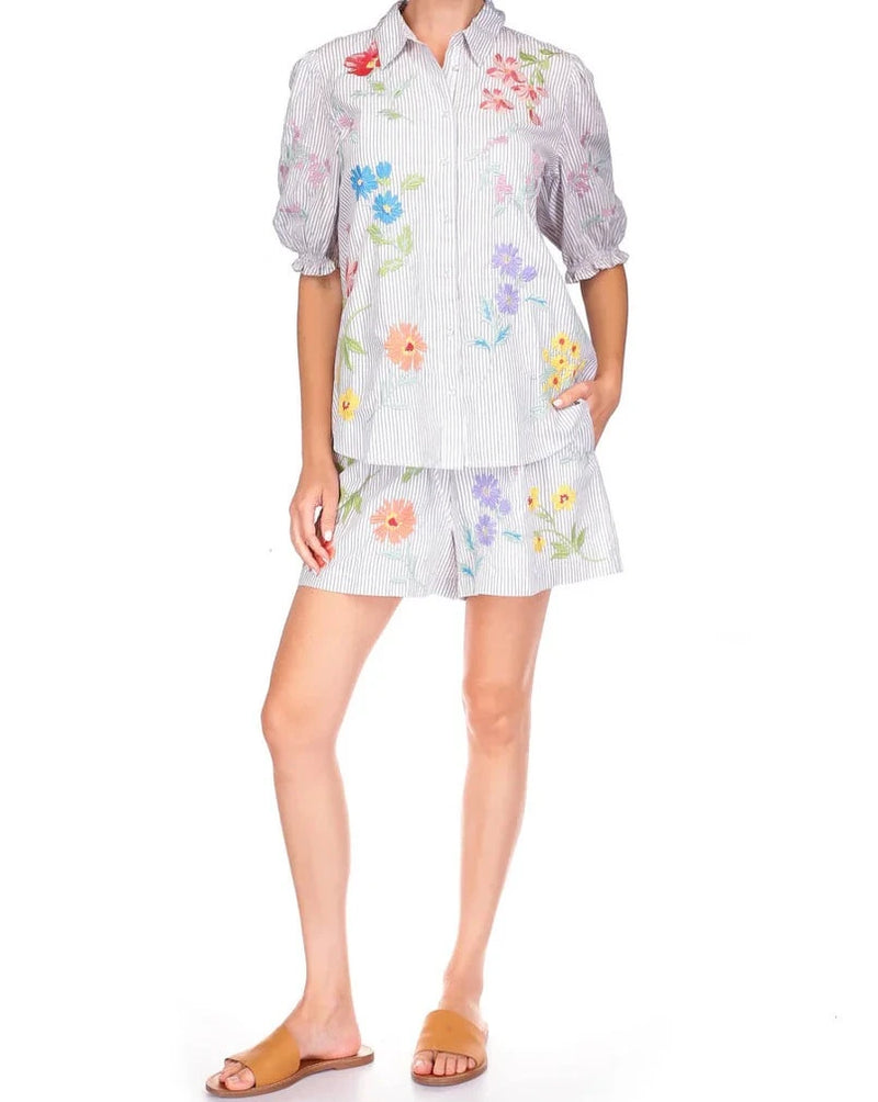 Woman wearing button front short sleeve blouse with grey and white lines, floral embroidery and puff sleeves