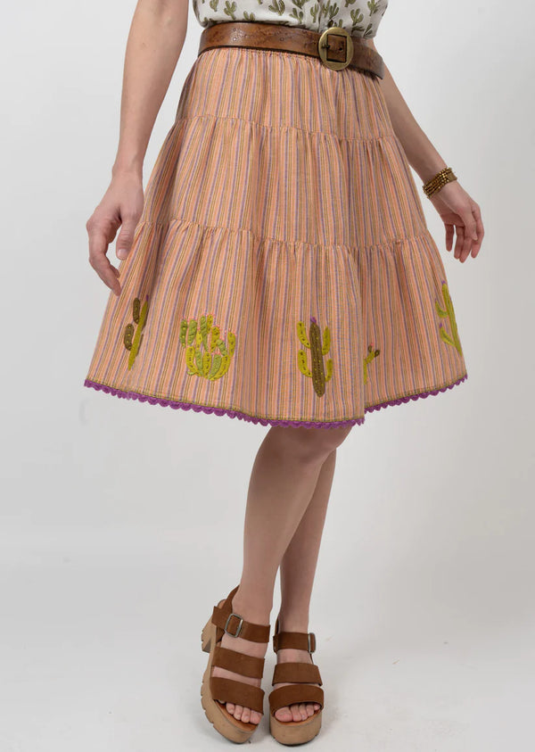 Woman wearing skirt that is tiered with embroidered cactus on the bottom 