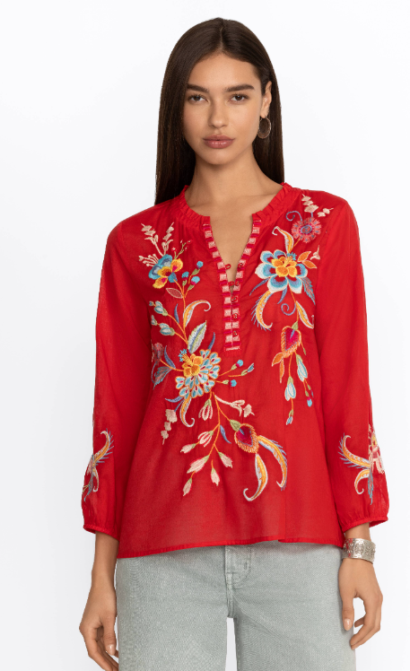 Woman wearing red blouse with long sleeve, button detail and floral embroidery in multicolor