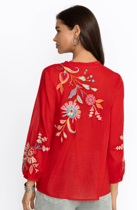 Woman wearing red blouse with long sleeve, button detail and floral embroidery in multicolor