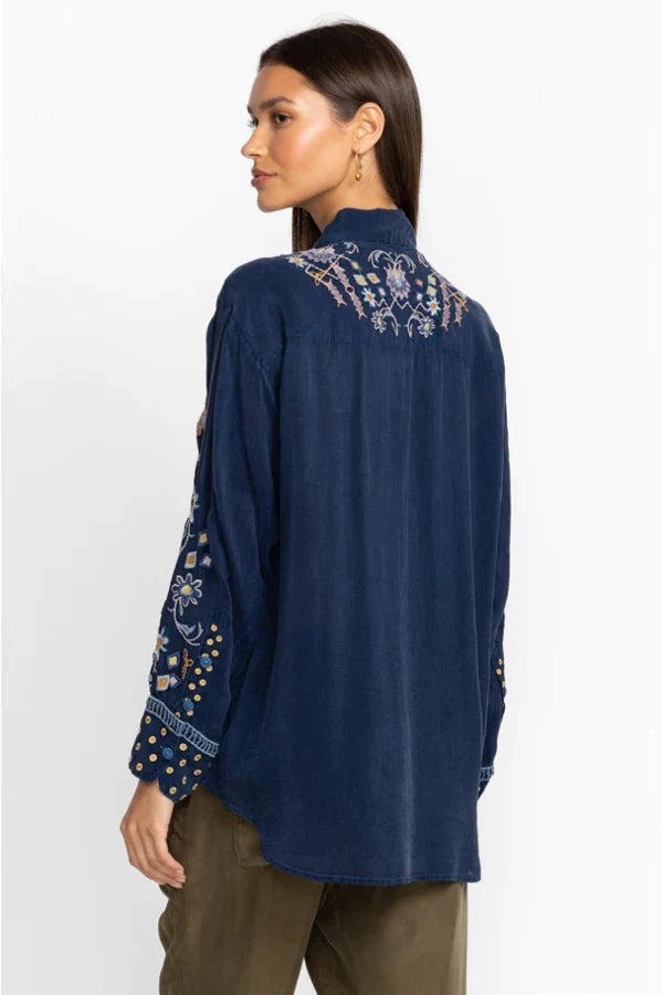 Woman wearing navy blouse that is delicately adorned with intricate placement embroidery and stunning detail