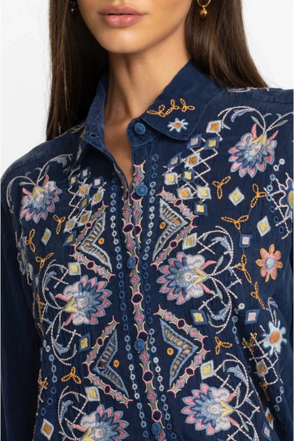 Woman wearing navy blouse that is delicately adorned with intricate placement embroidery and stunning detail