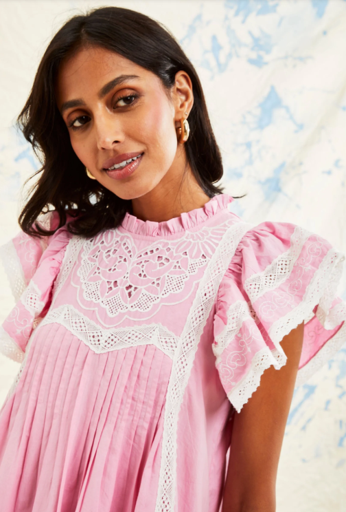 Woman wearing pink baby doll dress with eyelet detail and puff sleeve