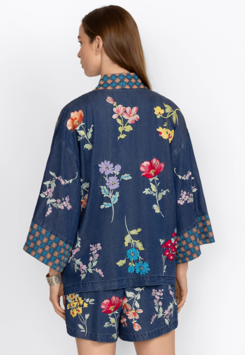 Woman wearing tensile kimono with floral embroidery all over with geometric pattern around the cuffs and neckline