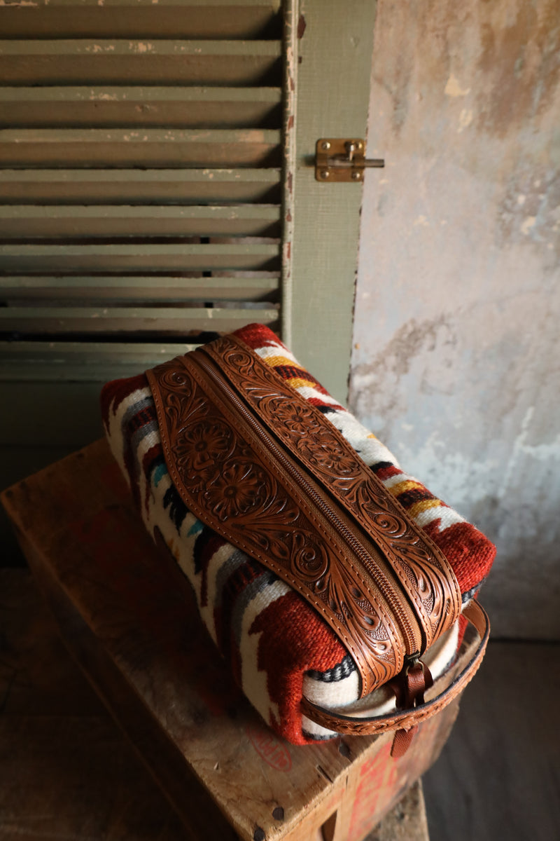 Shave kit or cosmetic bag with Aztec pattern that is embellished by tooled leather. Zipper closure and handle for easy travel