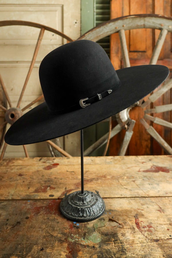 Black cowboy hat on a stand with rustic wooden background