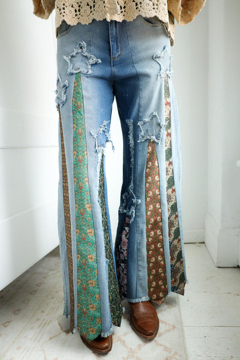 Person wearing a floral blouse and ripped jeans with a patterned ties on it in a bright room.