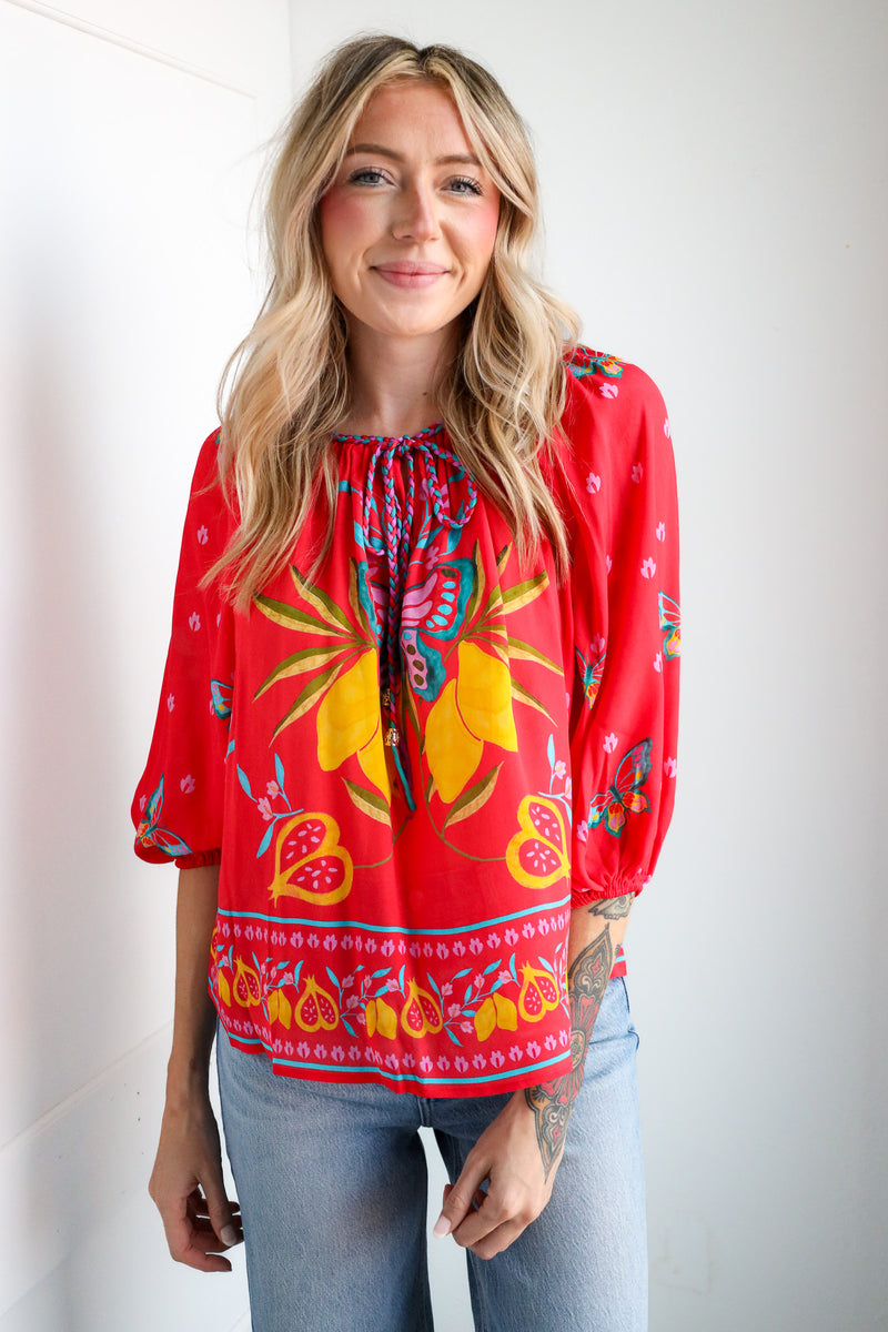 Woman wearing a red floral blouse with a plain background