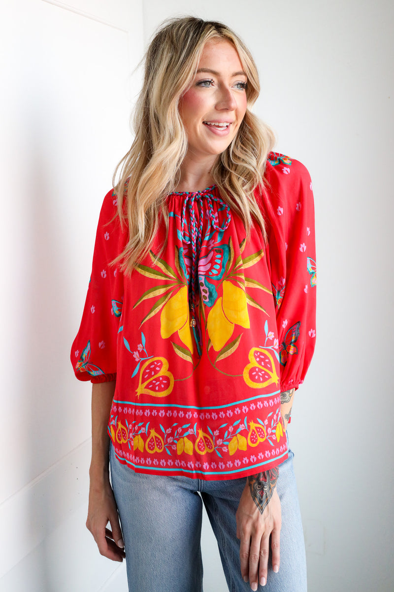 Woman wearing a red floral blouse with a plain background