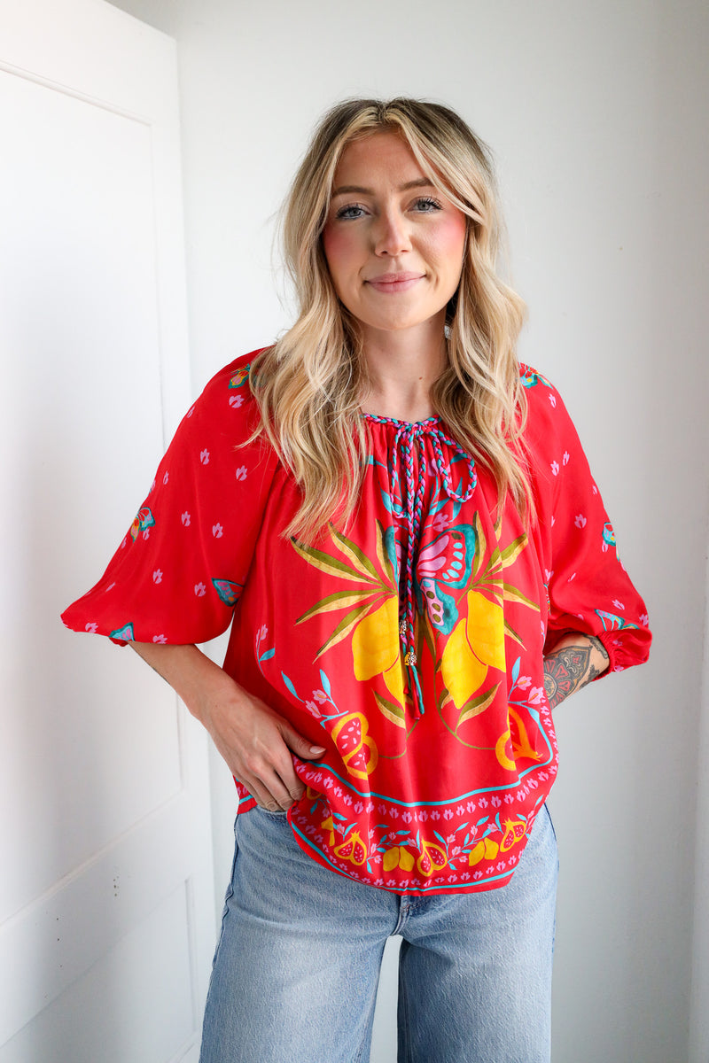 Woman wearing a red patterned blouse with a plain background