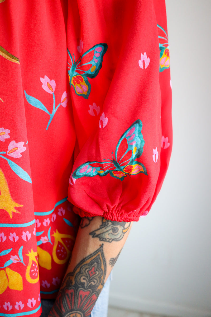 Red shorts with colorful butterfly and floral patterns on a plain background