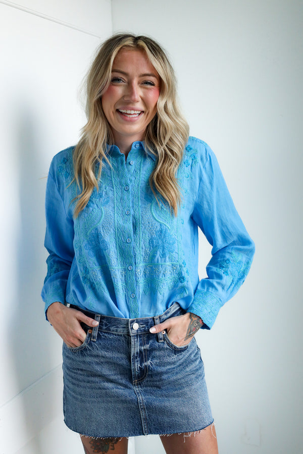 Woman wearing a blue denim shirt and skirt against a white wall