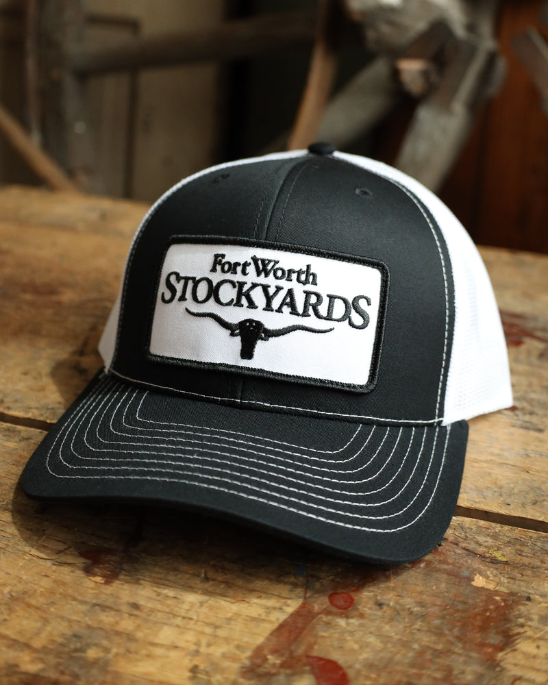 Black and white cap with Fort Worth Stockyards logo on a wooden surface
