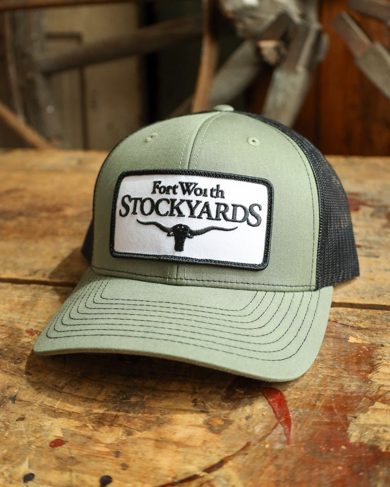 Green cap with 'Fort Worth Stockyards' logo on a wooden surface