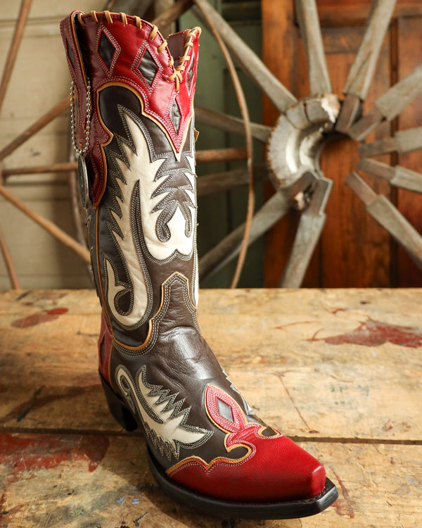 Decorative cowboy boot with intricate designs on a wooden surface.