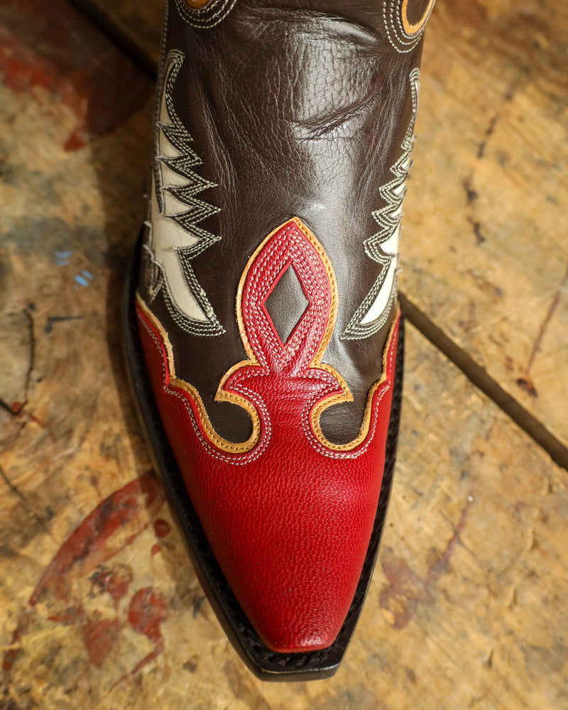Close-up of a cowboy boot with red and black design on a textured surface