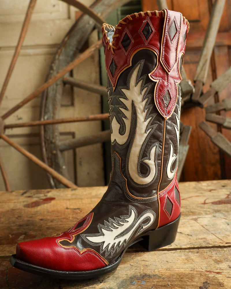 Cowboy boot with intricate designs on a wooden surface with a rustic background
