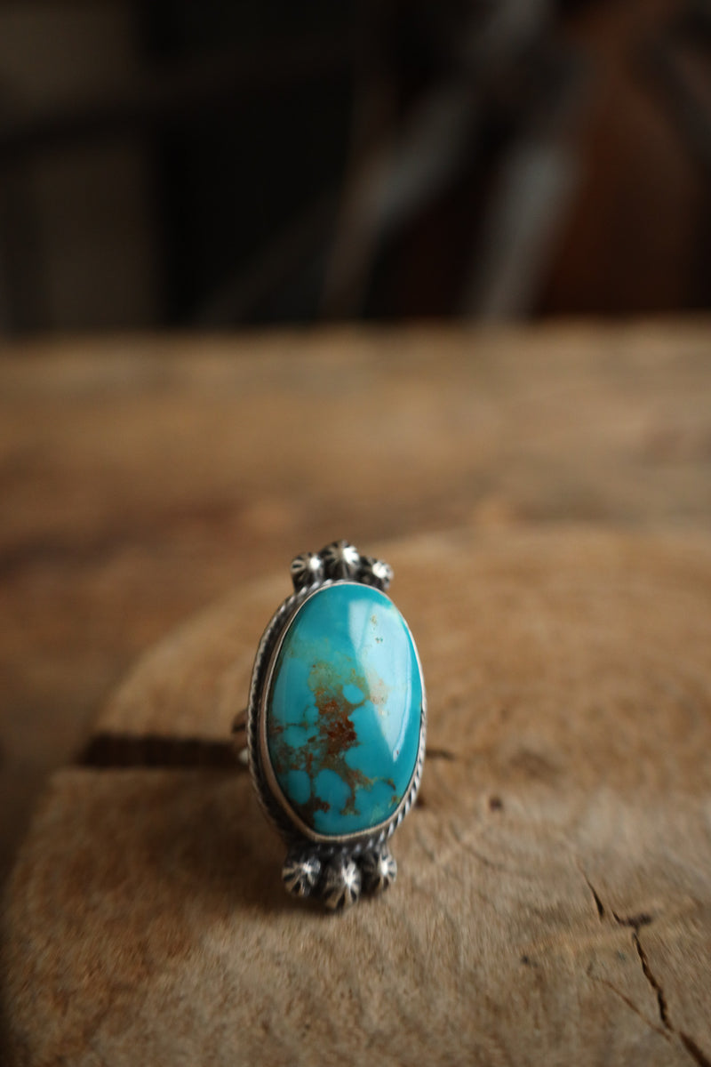 Turquoise ring with silver band on a wooden surface