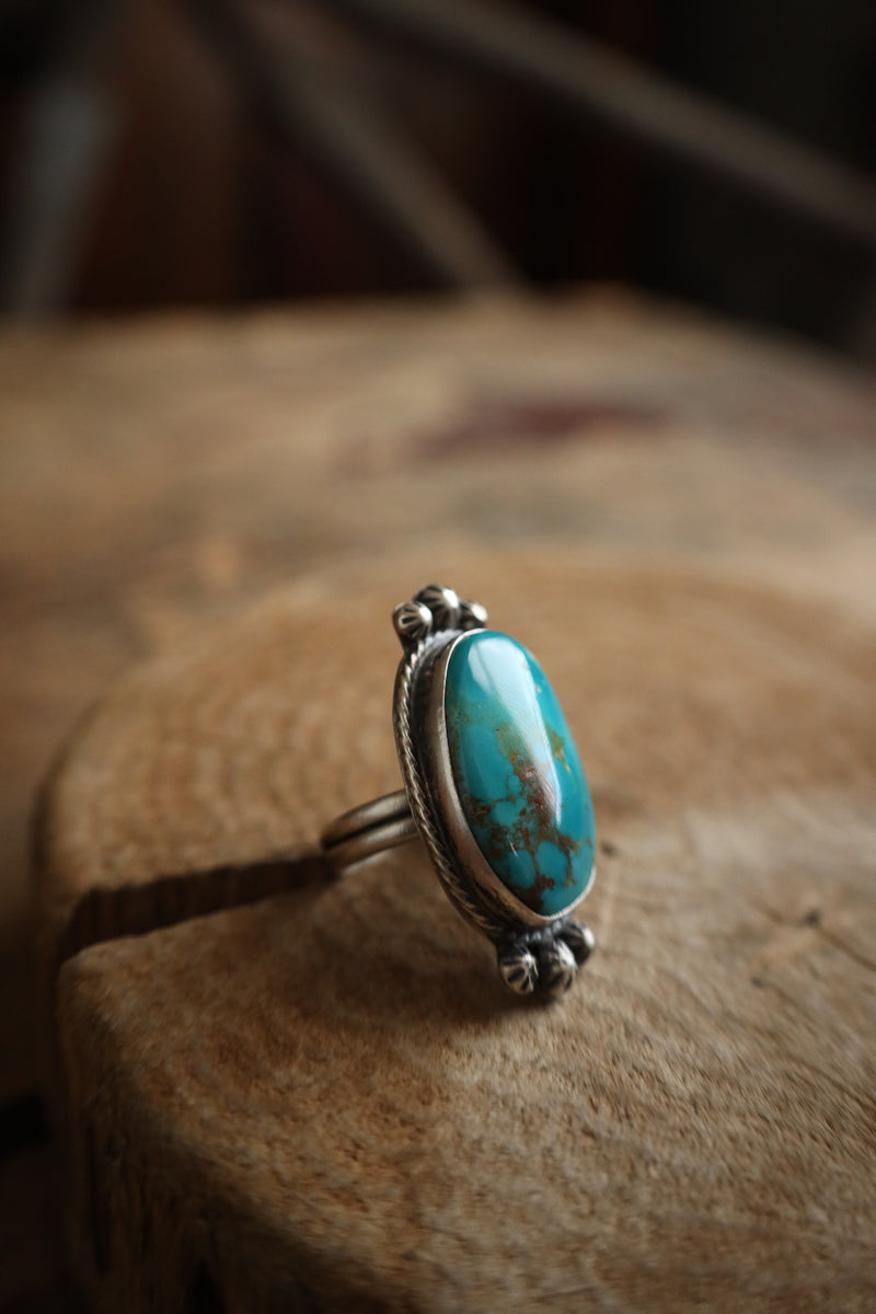 Turquoise ring with silver setting on a wooden surface