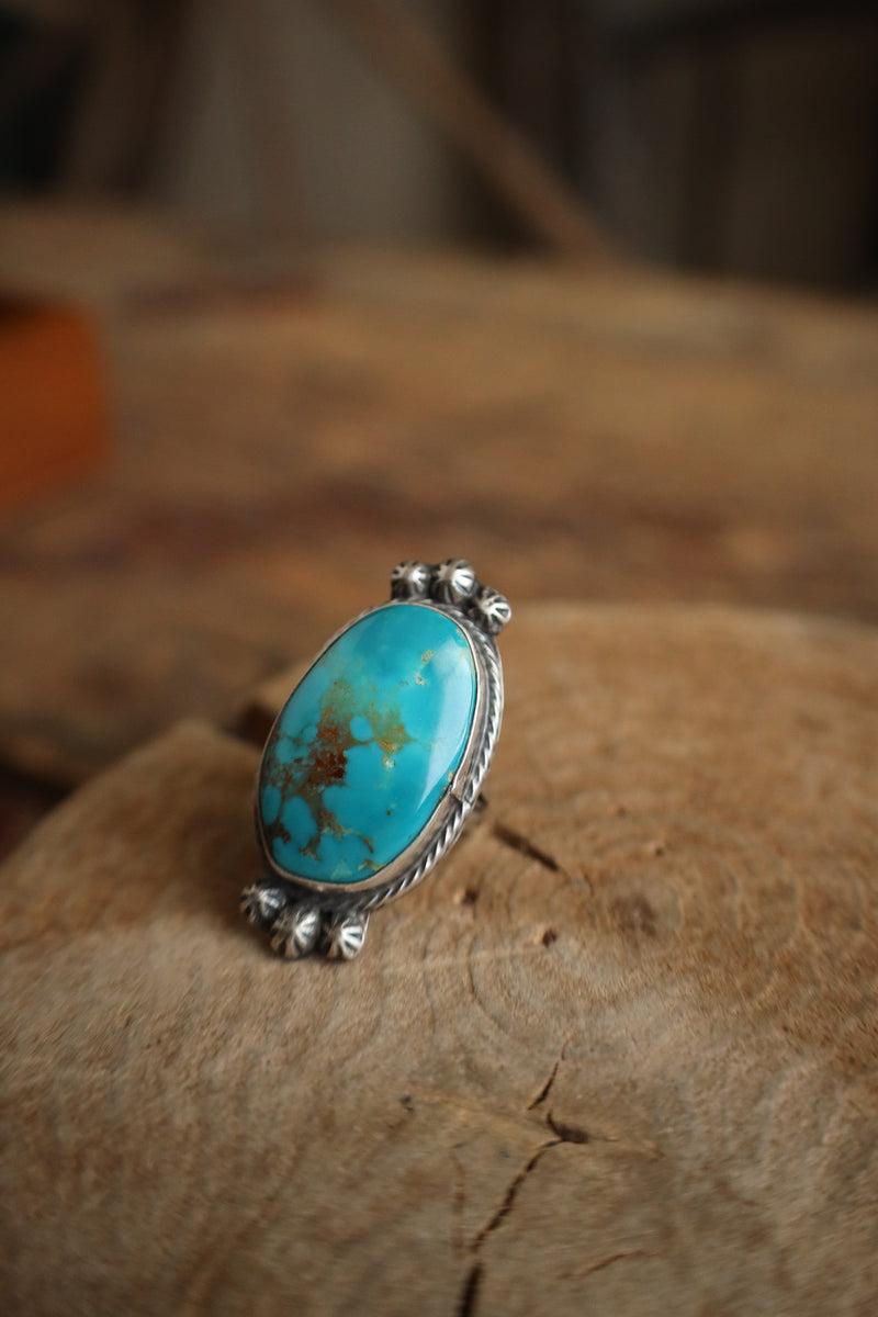 Turquoise ring with silver band on a wooden surface