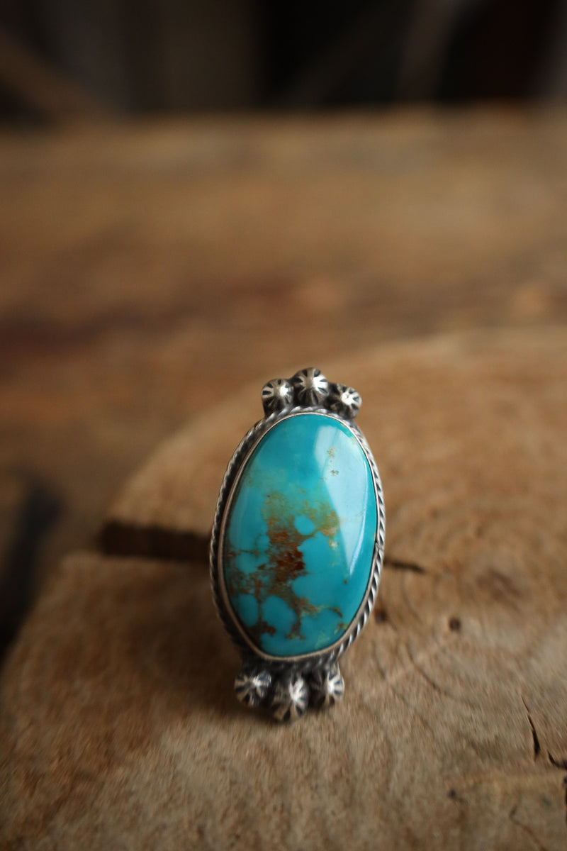Turquoise ring with silver band on a wooden surface