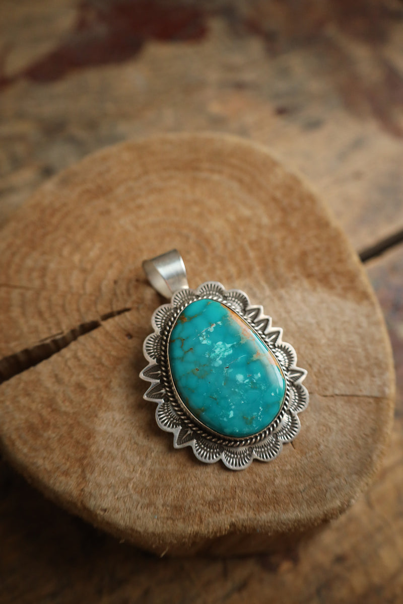 Turquoise pendant with silver setting on a wooden surface