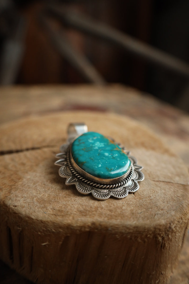 Turquoise pendant on a silver chain on a wooden surface