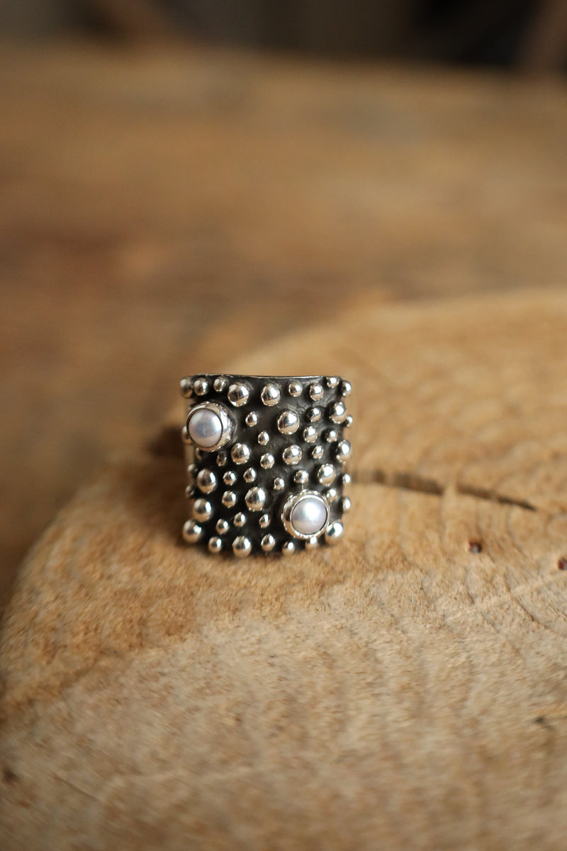 Silver ring with embedded stones on a textured surface