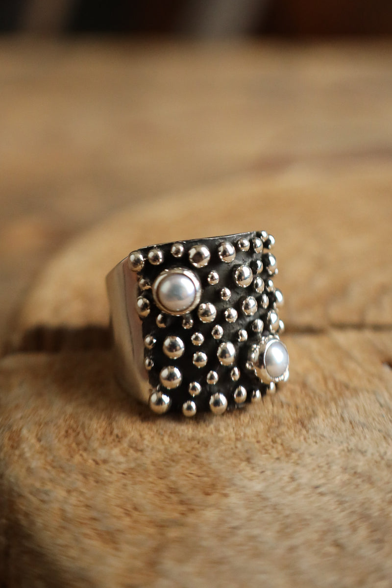 Silver ring with circular design on a wooden surface